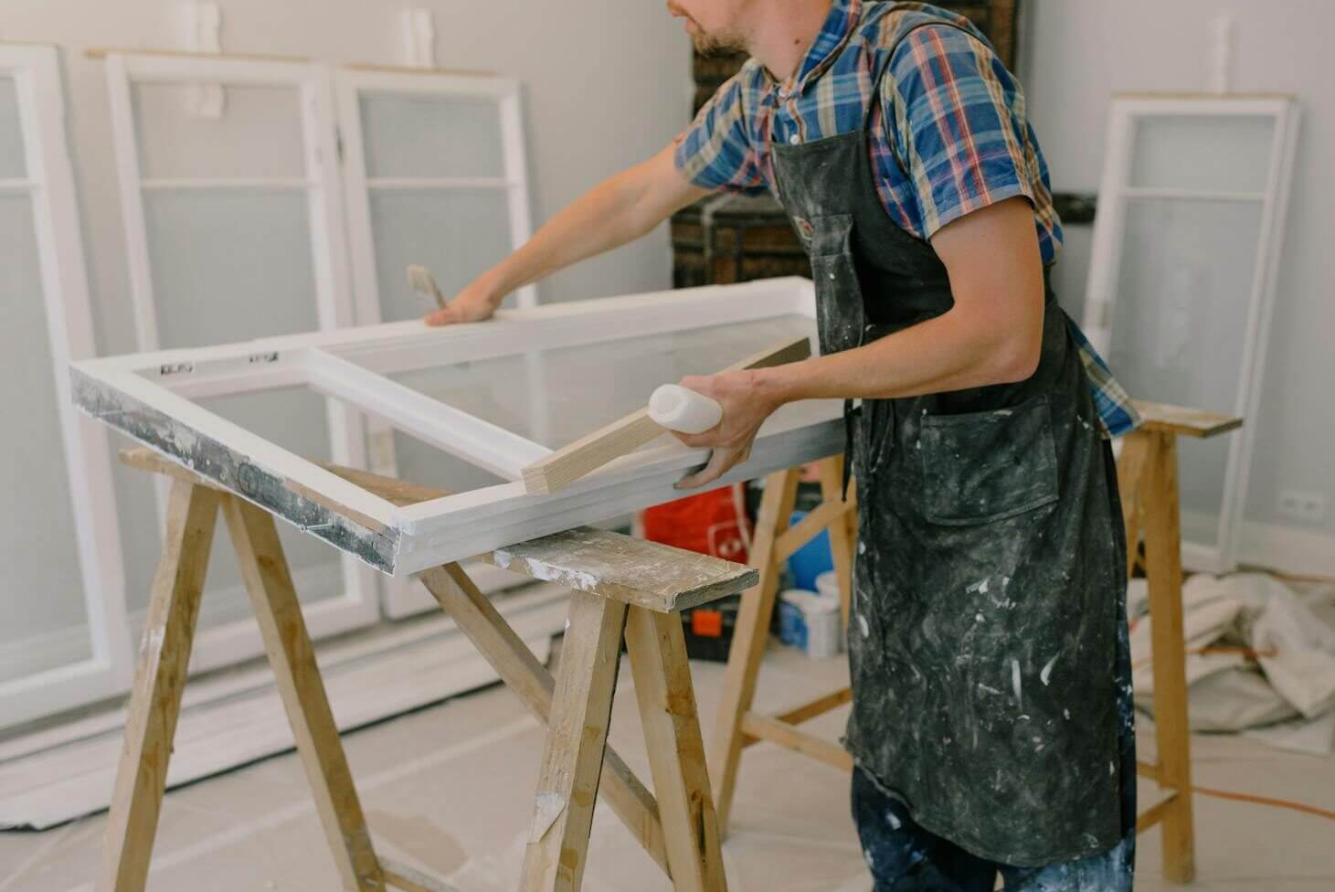 A skilled craftsman repairing a window frame indoors using tools and expertise.